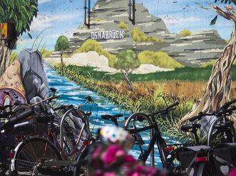 Bunte Graffiti-Kunst in Osnabrück, die die kreative und grüne Seite der Stadt zeigt, eingerahmt von parkenden Fahrrädern.